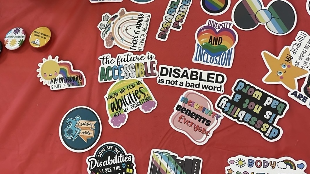 Photo of disability-themed stickers and pins on red tablecloth