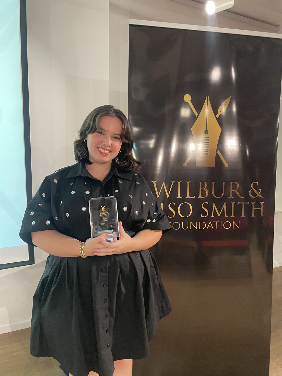 Woman holding award wearing formal clothing