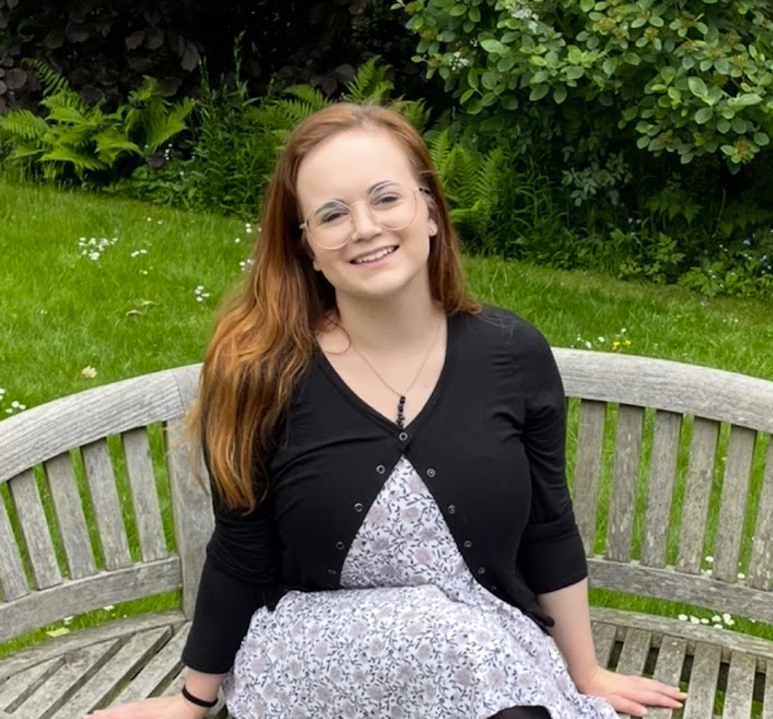 Profile picture of a smiling woman sitting on a bench