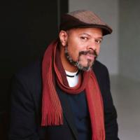 Photo of John Keene wearing brown hat and red scarf